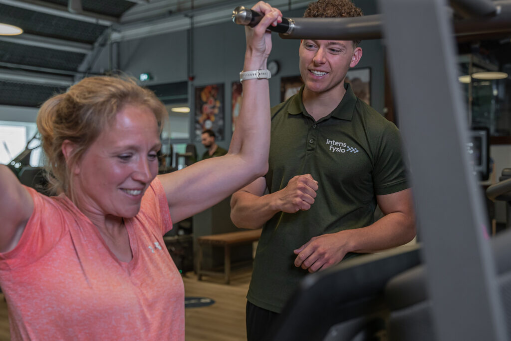 Vrouw voert EGYM oefening uit met trainer naast haar voor optimale begeleiding