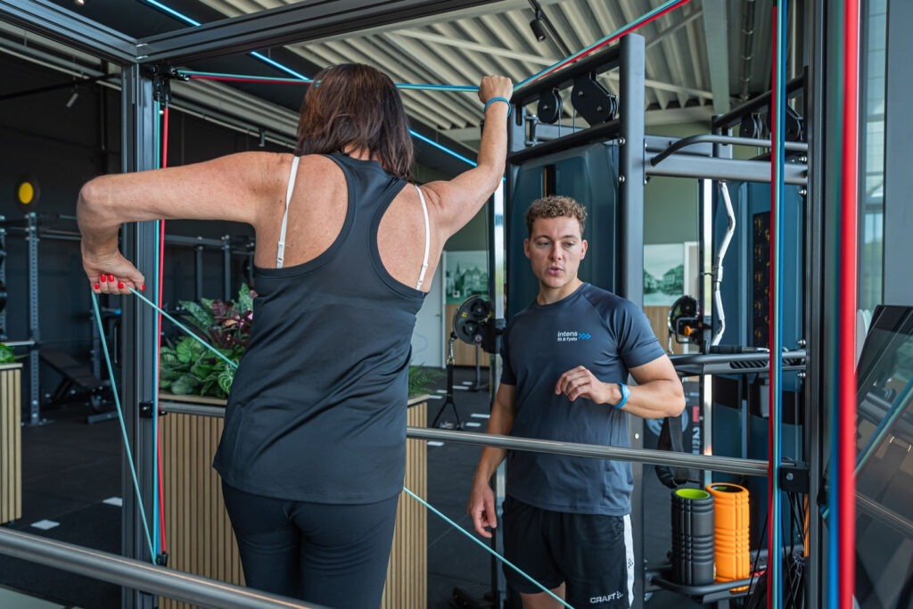Vrouwelijke sporter zit op fitflex oefeningen uit te voeren onder begeleiding van een Fitcoach